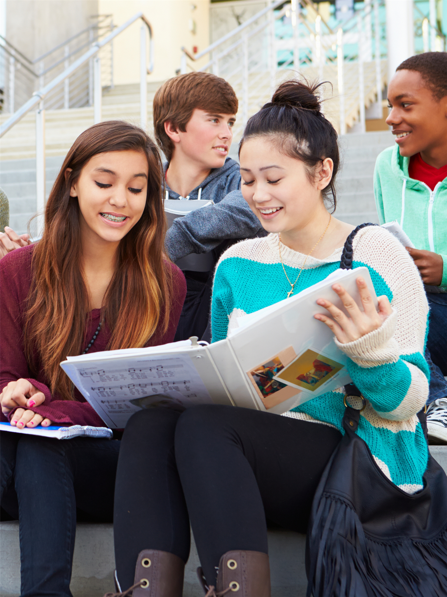 four students gather on the school steps to study